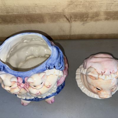 Sale Photo Thumbnail #192: Charming ceramic cookie jar featuring a mother pig in a blue dress and bonnet holding two piglets with pink bows. The removable lid forms the mother pig's head. Glazed finish with light overall crazing consistent with age, minor paint wear, but no visible