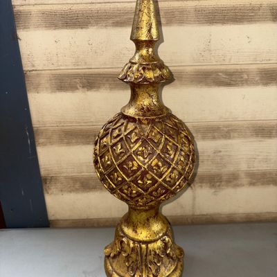 Sale Photo Thumbnail #333: Ornate decorative finial featuring a antiqued gold gilt finish over a dark base with detailed lattice, fleur-de-lis, and acanthus leaf carving/molding. Appears to be resin or composite material styled to look like carved wood. Good condition with light su