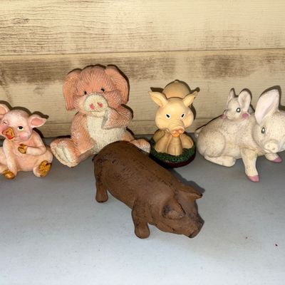 Sale Photo Thumbnail #24: A collection of 5 pig figurines in various materials and styles, including resin/ceramic figures and a cast iron style pig. Light surface wear consistent with display and age. No major chips or breaks observed.