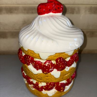 Sale Photo Thumbnail #176: Ceramic cookie jar shaped like a layered strawberry shortcake with a whipped cream lid topped with strawberries. Shows some light surface paint wear and minor distress to the painted detail, typical for vintage ceramics, but overall in good usable conditi