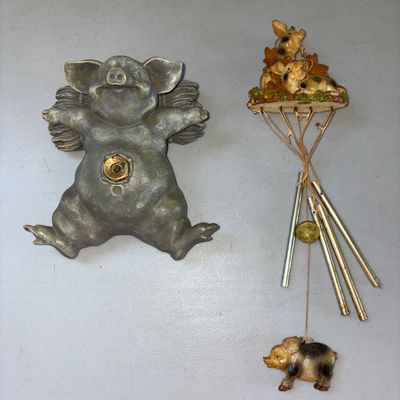 Sale Photo Thumbnail #12: Collection of pig-themed home decor items including:

1. Cast metal winged pig spigot or hose bib cover featuring a whimsical flying pig design with a brass fitting in the center.
2. Pig-themed wind chime featuring resin or ceramic pigs on top and as the 