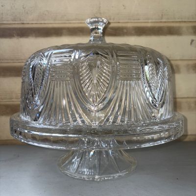 Sale Photo Thumbnail #330: Clear cut glass pedestal cake stand complete with a matching glass dome lid. Features detailed geometric and arch pattern cuts. Includes pedestal base, plate rim, and clear glass knob handle on the dome. Appears to be in good condition with no visible chi