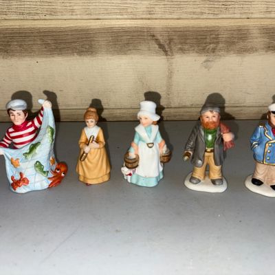 Sale Photo Thumbnail #135: A set of five hand-painted ceramic or porcelain miniature figurines with nautical themes. Includes a fisherman with a net full of sea life, a woman with a spyglass, a woman carrying water buckets, a bearded sailor with a telescope, and a ship captain in a