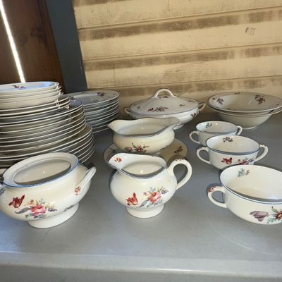 Sale Photo Thumbnail #290: Large set of fine porcelain or china dinnerware featuring delicate hand-painted style floral bouquets and blue rim trim. Includes dinner plates, side plates, saucers, dual-handled soup bouillon cups, a creamer, covered sugar bowl, gravy boat with attached