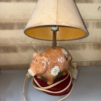 Sale Photo Thumbnail #22: Small ceramic novelty accent lamp featuring a hand-painted floral pig on a red oval base, paired with a tapered fabric shade. Includes attached power cord with inline switch. The lamp shade shows noticeable discoloration/staining from age and use. Unteste
