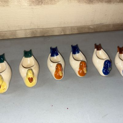 Sale Photo Thumbnail #80: A set of 6 glazed ceramic duck-shaped rests, likely intended for chopsticks or knives. Includes three color variations with two of each design featuring hand-painted details in yellow, orange, green, blue, and brown. Items show minor age-related surface w