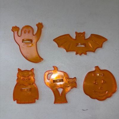 Sale Photo Thumbnail #301: Set of 5 translucent orange plastic Halloween cookie cutters featuring iconic shapes: a ghost, bat, owl, black cat in a tree/crescent shape, and a pumpkin / jack-o'-lantern. Each piece features a built-in plastic handle on the back. Marked 'Made in China'