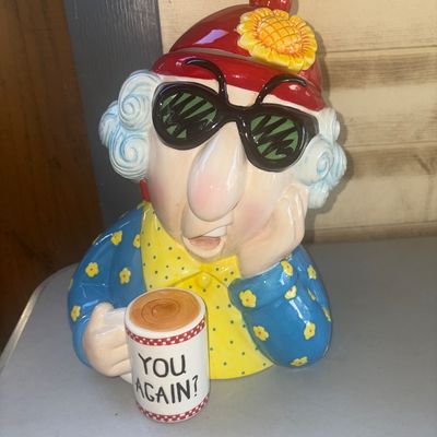 Sale Photo Thumbnail #241: Ceramic novelty cookie jar depicting an elderly character wearing sunglasses and a red beanie with a flower, holding a coffee mug that reads "YOU AGAIN?". Brightly painted glazed ceramic finish. Appears in good overall condition with no visible chips or c