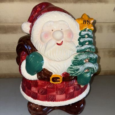 Sale Photo Thumbnail #201: A vintage glazed ceramic Santa Claus cookie jar dated 1998 on the star atop the Christmas tree. Features Santa in a red plaid coat holding a small decorated tree and a toy sack. Two-piece design with removable lid/head. Glazed finish in vibrant reds, gree
