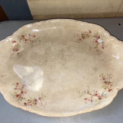 Sale Photo Thumbnail #380: Large oval ceramic serving platter with scalloped rim and delicate floral transferware pattern. Features significant age-related crazing and surface discoloration/patina, consistent with antique ironstone or semi-porcelain tableware.
16X11.5in