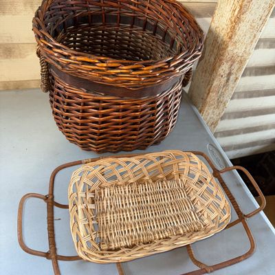 Sale Photo Thumbnail #64: Collection of 3 woven wicker items featuring a deep round reddish-brown wicker basket with braided handles, a rectangular light wicker tray basket, and a dark bentwood/rattan wire-style frame tray with handles. All pieces show light age-appropriate wear w