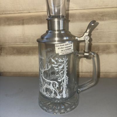 Sale Photo Thumbnail #243: Unique clear glass beer stein featuring an etched forest and stag design. Outfitted with a metal/pewter hinged lid that holds an integrated clear glass shot glass top. Has an original label stating "Glass Blank made in ITALY - all other components made in