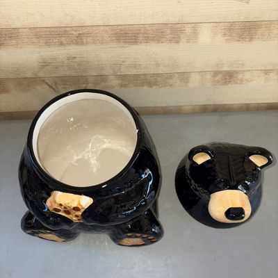 Sale Photo Thumbnail #169: Glazed ceramic cookie jar shaped like a sitting black bear holding a chocolate chip cookie. Removable head lid. Appears to be in good condition with no visible cracks or chips.
12in tall