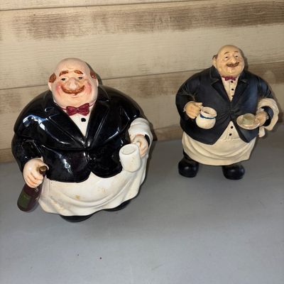 Sale Photo Thumbnail #52: 8.5X5.5in on cookie jar
8in tall on figure 
Pair of whimsical kitchen/bistro decor items featuring a ceramic waiter/chef cookie jar with removable lid and a matching resin waiter figurine. Items show light surface wear and minor discoloration on the apron