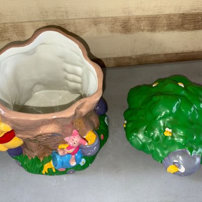 Sale Photo Thumbnail #51: 10X5in
Vintage ceramic cookie jar featuring Disney's Winnie the Pooh and Piglet around a tree trunk with a beehive lid inscribed 'Pooh's Hunny'. Shows some paint wear and minor scuffs, particularly on the beehive section of the lid, but overall in good us