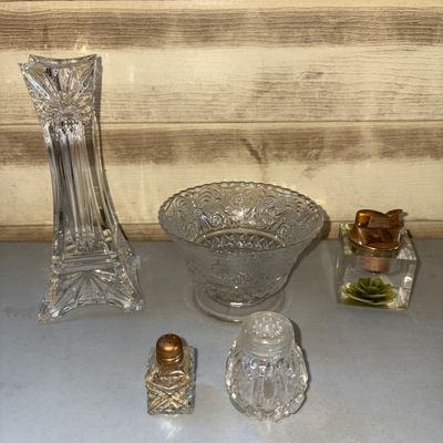 Sale Photo Thumbnail #221: An assortment of 5 vintage glass tableware and vanity items including: a tall cut glass vase/candlestick holder, a footed pressed glass bowl, a clear acrylic/resin desk table lighter with an embedded decorative base, a small square glass shaker with a met