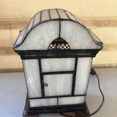Sale Photo Thumbnail #229: Vintage stained glass clock in a Tiffany-style arched mantle casing featuring opalescent and floral glass panels with Roman numerals on the clock face. Features a rear access door. Please note condition: power cord end is damaged/cut and requires repair/r