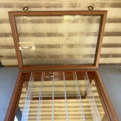 Sale Photo Thumbnail #149: Wooden tabletop display case featuring a hinged glass lid, brass-tone latch closures, acrylic interior dividers, and a mirrored base. Ideal for displaying pocket knives, jewelry, coins, or small collectibles. Shows light scuffs and minor surface wear cons