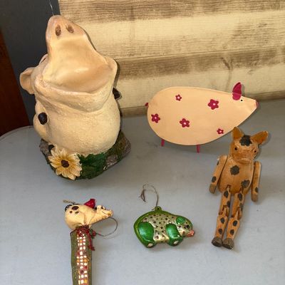 Sale Photo Thumbnail #300: A 5-piece collection of pig-themed home decor items and ornaments. Includes a large wide-mouth ceramic or resin pig holder/planter featuring sunflower accent details, a painted metal pig cutout with floral pattern, a jointed wooden spotted pig figure, a m