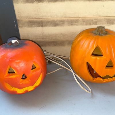 Sale Photo Thumbnail #387: Pair of orange molded plastic or blow mold Jack-O'-Lantern Halloween decorations with built-in light cords and power plugs. Features classic cutout jack-o'-lantern faces. Shows light surface wear, scuffs, and minor paint loss near the stem on one pumpkin 