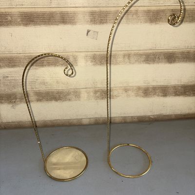Sale Photo Thumbnail #141: A pair of brass-colored or gold-tone textured metal hanging display stands, ideal for showcasing Christmas ornaments, pocket watches, or small hanging decor items. Features twisted wire detailing and circular bases. Includes two different heights. Both ar