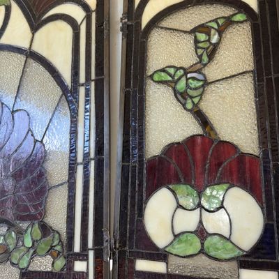 Sale Photo Thumbnail #328: A 3-panel hinged stained glass fireplace screen featuring an intricate Art Nouveau floral/fan pattern in shades of deep red, green, cream, and textured clear glass. Heavy leaded metal framework with hinges connecting the side panels to the central arched 