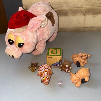 Sale Photo Thumbnail #21: A collection of small animal figures and a plush pig wearing a Santa hat. Includes a plush pink pig with brown spots and a red hat, a blown glass patterned pig figurine, small resin/plastic pig and bear figurines, a wooden Disney alphabet block, and other