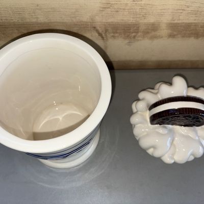 Sale Photo Thumbnail #196: A collectible ceramic Oreo cookie jar featuring a milk glass / milkshake design with whipped cream and a giant Oreo cookie on the lid. Front is decorated with the classic blue Oreo logo and the tagline "America's Favorite Cookie". The container is two pie