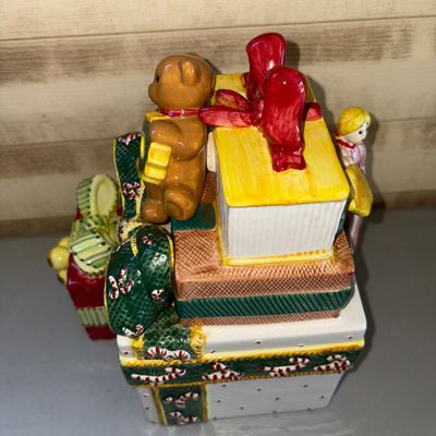 Sale Photo Thumbnail #186: Hand-painted ceramic festive table decor set featuring a stacked gift box cookie jar/container adorned with a teddy bear, a girl holding a 'Happy Holidays' sign, candy canes, and festive bows, accompanied by a smaller matching gift box ceramic piece. Appe