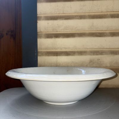 Sale Photo Thumbnail #378: A large, classic white ceramic or ironstone wash basin bowl featuring a wide rolled rim. Shows light age-related wear, minor surface discoloration, and fine crazing consistent with age and use. Ideal for rustic, farmhouse, or traditional decor.
16in