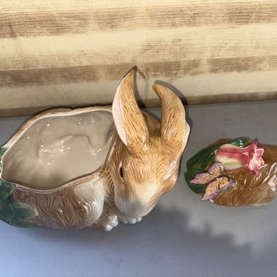 Sale Photo Thumbnail #235: Decorative hand-painted glazed ceramic rabbit cookie jar or covered dish featuring a butterfly and pink flower on the removable lid. Shows a small paint chip/flake on the rim under the lid area as visible in close-up photos. Otherwise in good overall cond