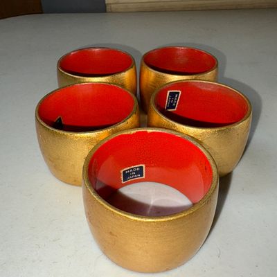 Sale Photo Thumbnail #70: Set of 5 vintage Japanese napkin rings featuring a metallic gold leaf finish on the exterior and a bright red lacquered interior. Original 'Made in Japan' paper labels remain intact inside several rings. Overall good condition with minor finish wear consi