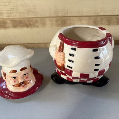 Sale Photo Thumbnail #59: 9in tall. 
Hand-painted ceramic cookie jar featuring an Italian chef in a white toque, red neck scarf, and checkered pants, holding a spoon or rolling pin. Shows minor surface wear, fine crazing in the glaze, and small paint scuffs consistent with age and