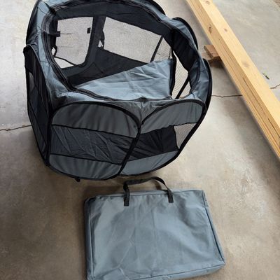 Sale Photo Thumbnail #105: 29X29X33in 
Gray and black mesh portable pop-up pet playpen or exercise pen. Features mesh windows for airflow and visibility, a removable zippered top/cover, and comes with a matching fabric carrying storage case with handles. Appears gently used in clea