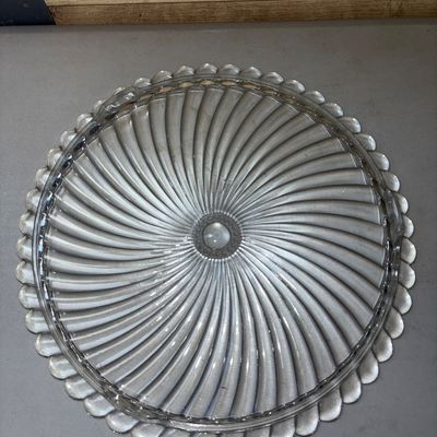 Sale Photo Thumbnail #323: Clear pressed glass platter or cake plate tray featuring a radial spiral/swirl design and a scalloped outer rim. Appears in good pre-owned condition with no visible chips or cracks. Light surface wear consistent with age and use.
11.5in
