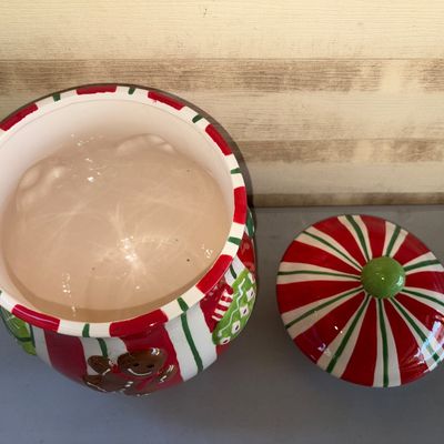 Sale Photo Thumbnail #198: Festive ceramic Christmas cookie jar with lid, featuring red, green, and white stripes, relief gingerbread man, and present accents. Clean interior with no visible cracks or major chips. Great holiday kitchen decor item.
13in tall
