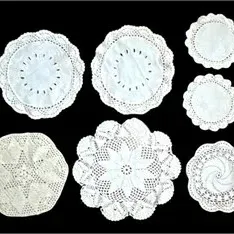 Collection of seven vintage white crocheted and lace doilies in various sizes and floral geometric patterns.