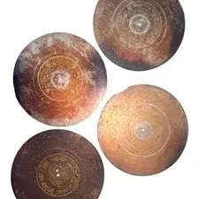 Set of four antique round Asian brass or bronze plates featuring concentric etched circular details and central medallions.