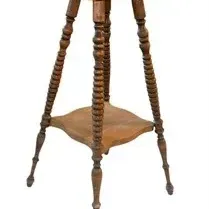 Antique wooden plant stand featuring spool-turned legs, a lower display shelf, and a square top surface.