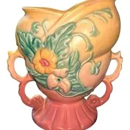 Vintage Hull art pottery vase featuring embossed floral and leaf details in soft yellow, pink, and green tones.