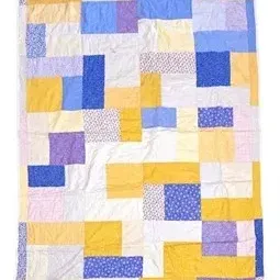 Handmade patchwork quilt featuring geometric color blocks in shades of blue, yellow, purple, and white.