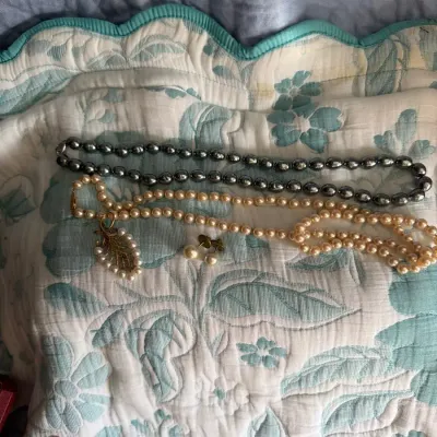 Assorted jewelry lot featuring a long gray bead necklace, cream-colored pearl-style strands, pearl d