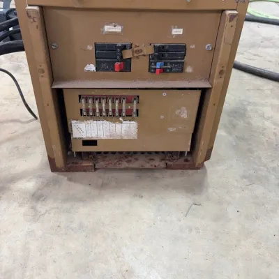 Sale Photo Thumbnail #90: Vintage tan metal electrical transfer switch panel for RV or marine use, featuring circuit breakers and fuse slots.