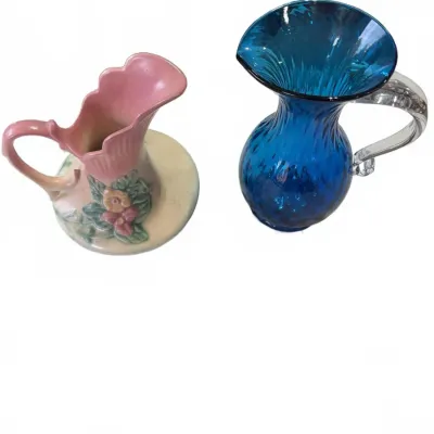 Sale Photo Thumbnail #289: Vintage ceramic floral pitcher alongside a hand-blown cobalt blue glass pitcher featuring an applied clear glass handle.