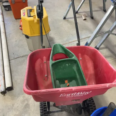 Sale Photo Thumbnail #47: Red EarthWay EV-N-SPRED walk-behind lawn spreader featuring a green plastic hand scoop inside the hopper.