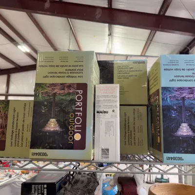 Sale Photo Thumbnail #247: Stack of boxed Portfolio and Malibu brand low-voltage outdoor landscape lights displayed on a metal shelf.