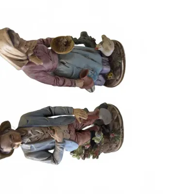 Sale Photo Thumbnail #299: Pair of vintage Capodimonte-style porcelain figurines depicting a peasant man with a shovel and a woman with a goose, both in detailed matte painted finishes.