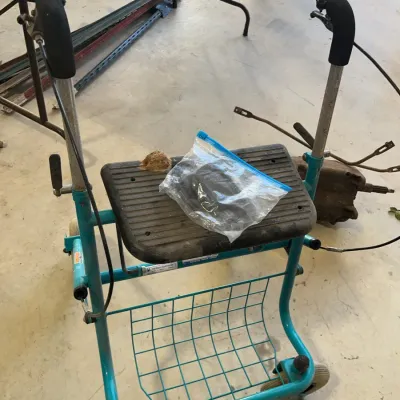 Sale Photo Thumbnail #36: Teal four-wheeled rolling walker with a padded seat, wire storage basket, and hand brakes, showing signs of wear and tear.