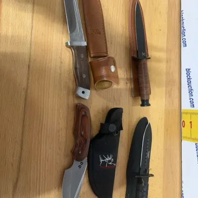 Sale Photo Thumbnail #145: Collection of four fixed-blade tactical and hunting knives with matching leather and nylon sheaths, including a Buck USA knife.