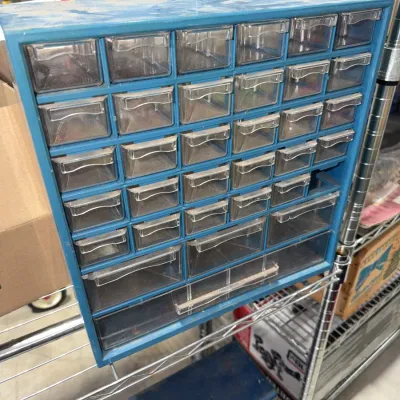 Sale Photo Thumbnail #209: Vintage blue plastic multi-drawer parts organizer with clear pull-out bins, showing light surface dust and wear.